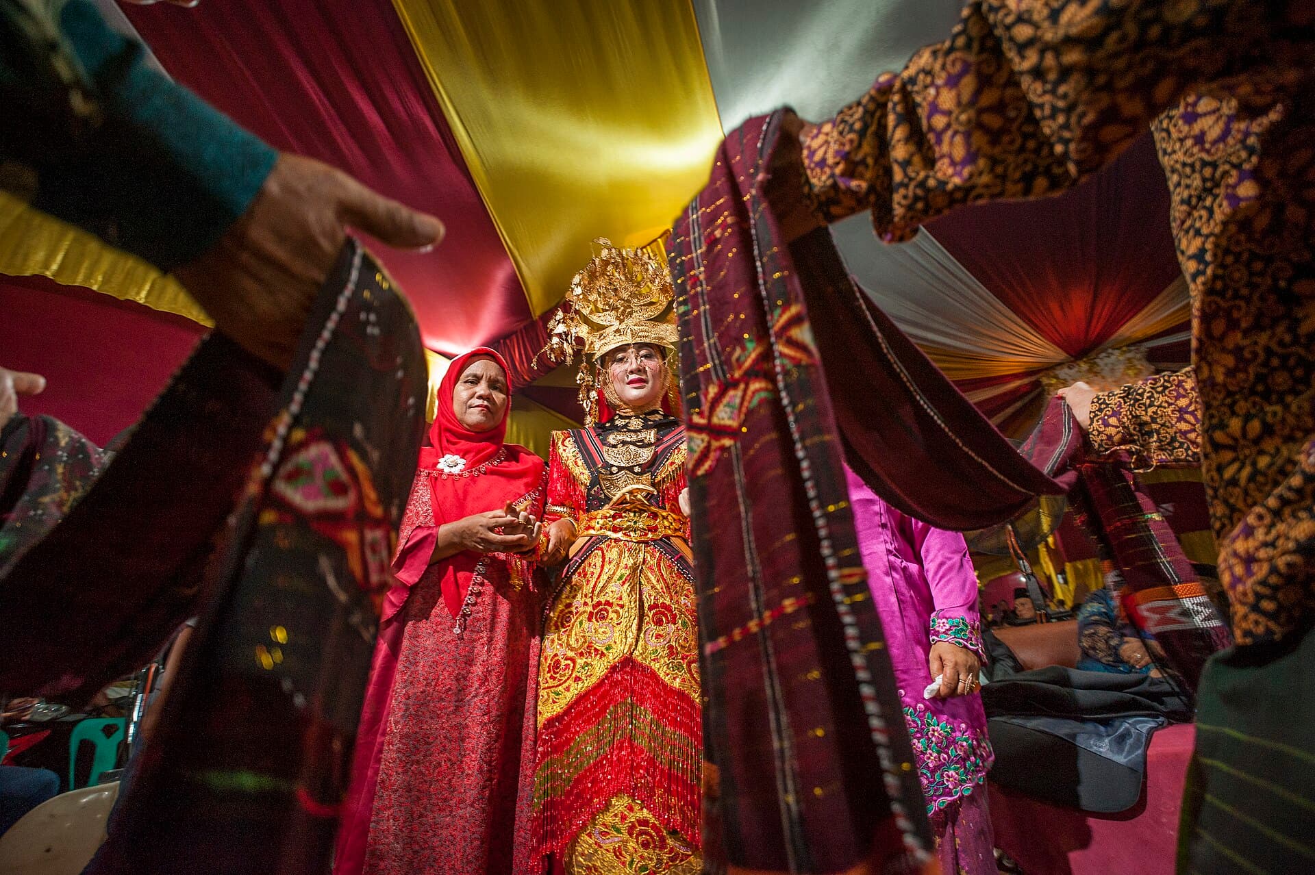 Pengantin adat Batak dalam upacara pernikahan tradisional, dengan kain adat yang diangkat keluarga